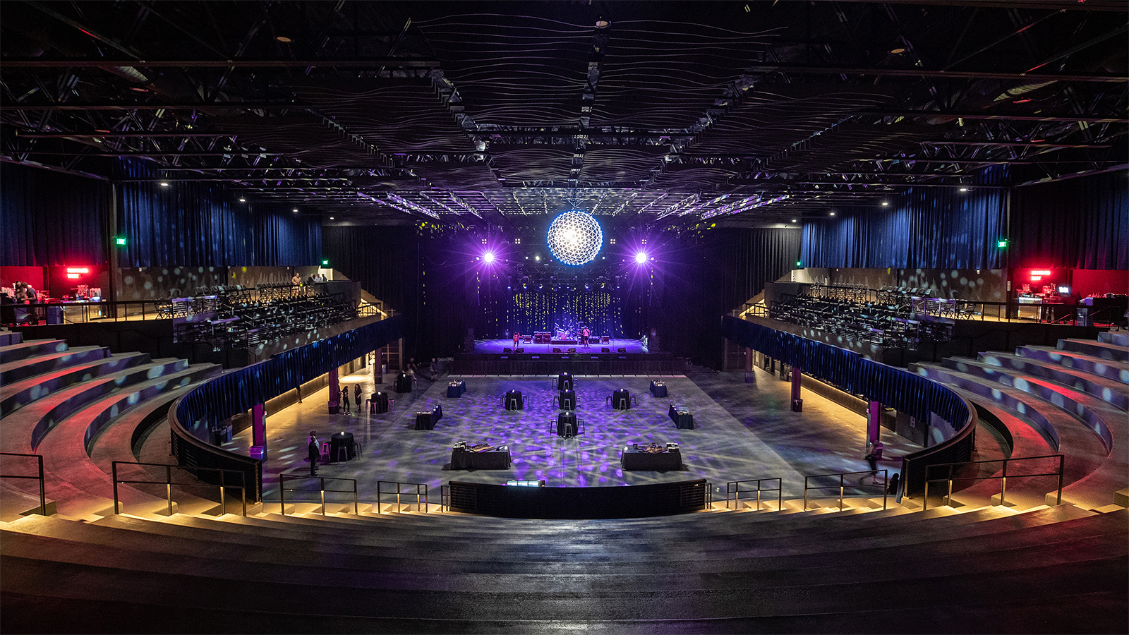 Tiered seating and dance floor facing the stage under a disco ball
