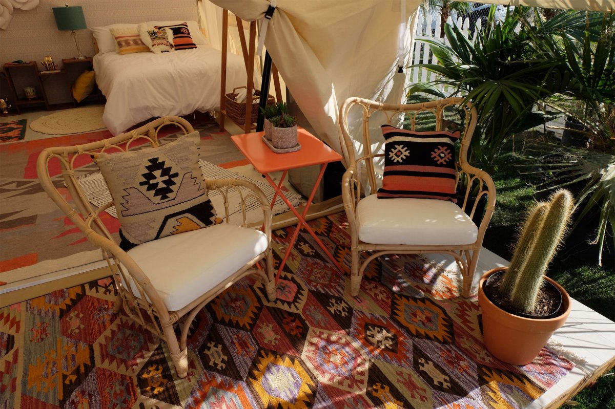 Image of two chairs with a bed in the background decorated in tribal print under a tent similar to a teepee