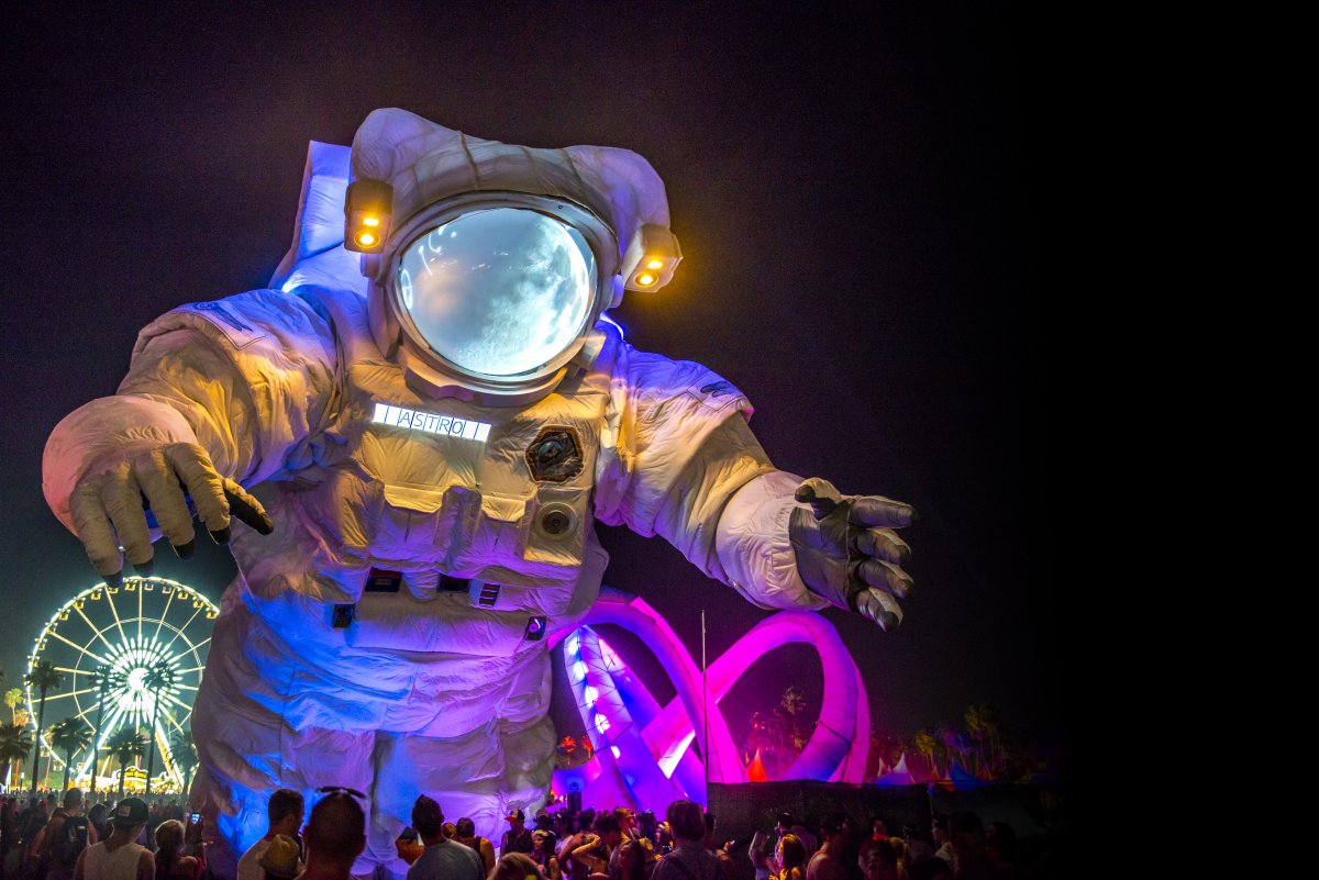 Image of a large astronaut art installation with a ferris wheel in the background during night time