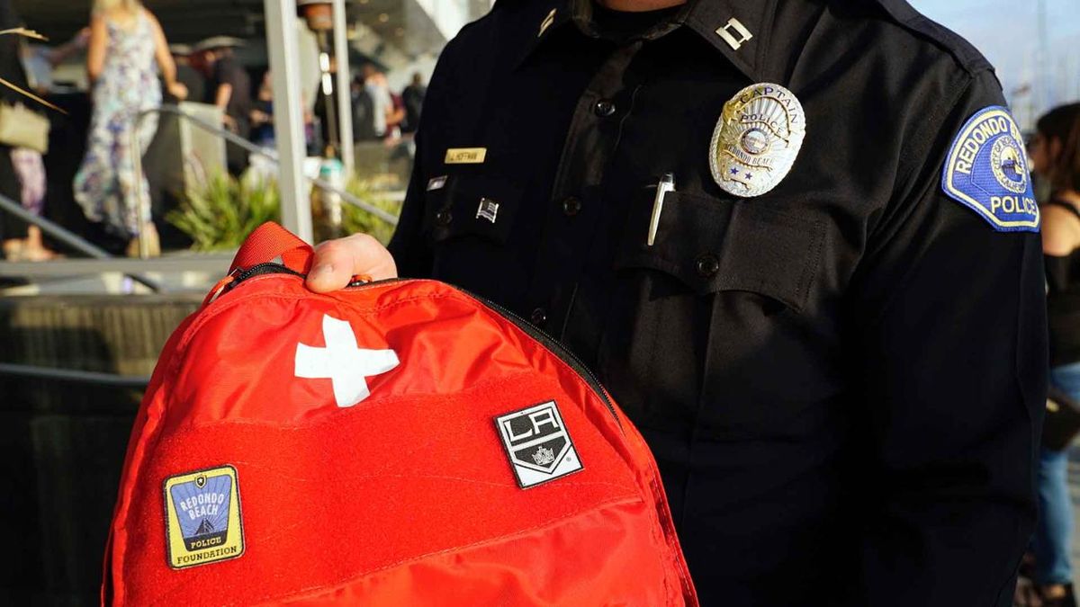 A Redondo Beach police officer holds an emergency safety kit that the LA Kings will distribute to local schools from the proceeds from the hockey club's Taste of South Bay event. 