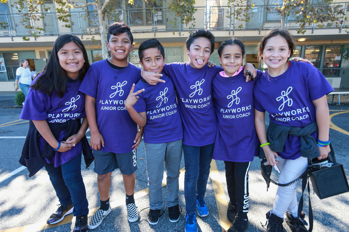 A group of Playworks Junior Coaches pose for a group photo on the playground of Magnolia Elementary during recess at AEG's Service Day. 