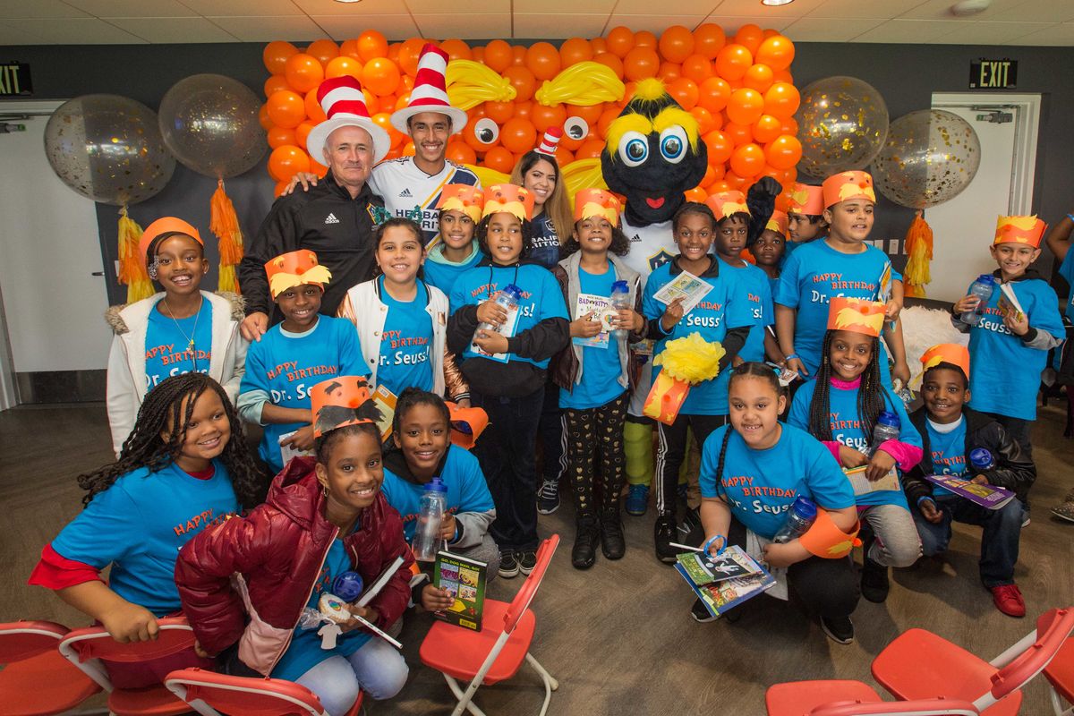 LA Galaxy staff and students from surrounding elementary schools in Carson pose in front of balloons holding books during the LA Galaxy's Read Across America Day Celebration at Dignity Health Sports Park. 