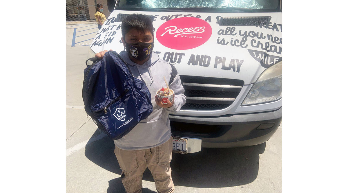 A student from 10th Street Elementary holds up his LA Galaxy backpack and ice cream from AEG. 