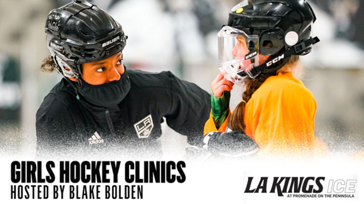 Tight shot of Blake Bolden in a Kings jacket and helmet speaking with a young girl in a yellow hockey jersey and helmet on the ice rink.