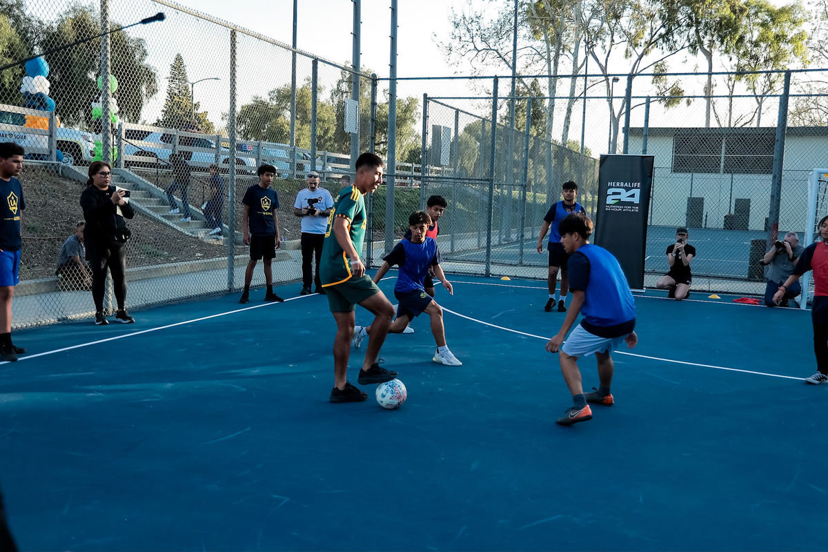 Children play with LA Galaxy's Aguirre on the new mini-pitch fields installed in Long Beach earlier this year.