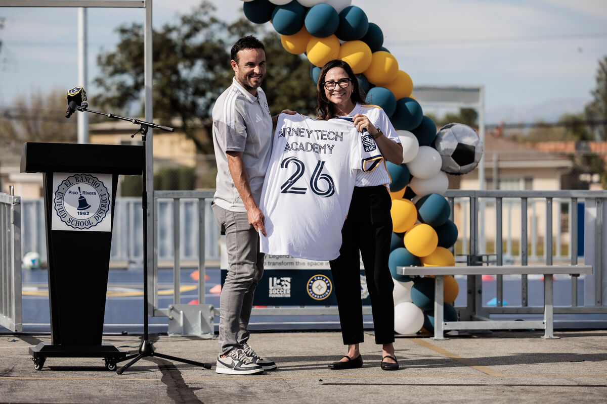 LA Galaxy legend Landon Donovan and an official holding a custom "Birney Tech Academy" jersey.