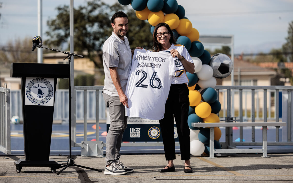 LA Galaxy legend Landon Donovan and an official holding a custom "Birney Tech Academy" jersey.